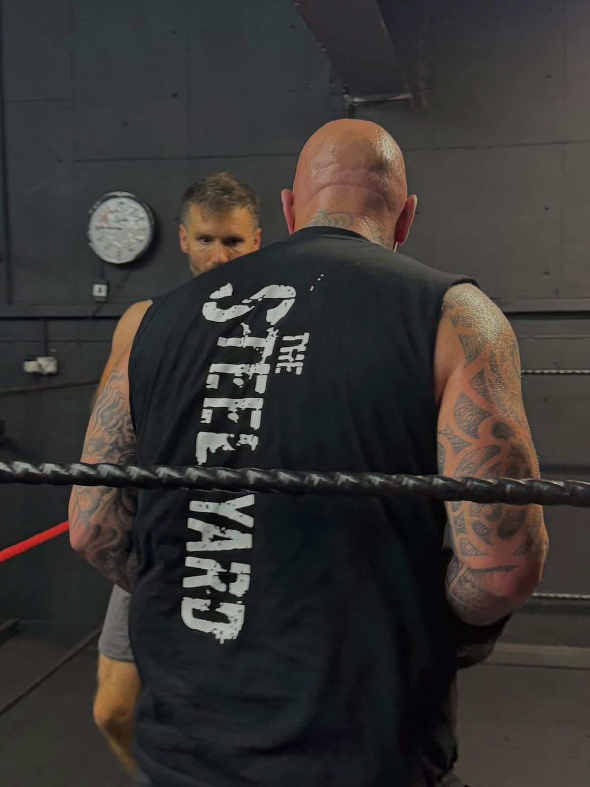 A member wearing a Steel Yard vest beside the boxing ring ropes.