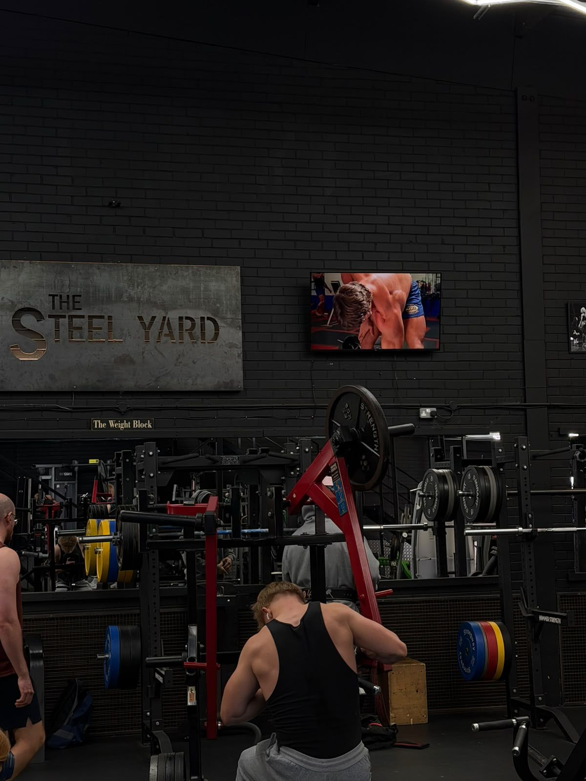 A member using plate-loaded equipment under The Steel Yard sign.